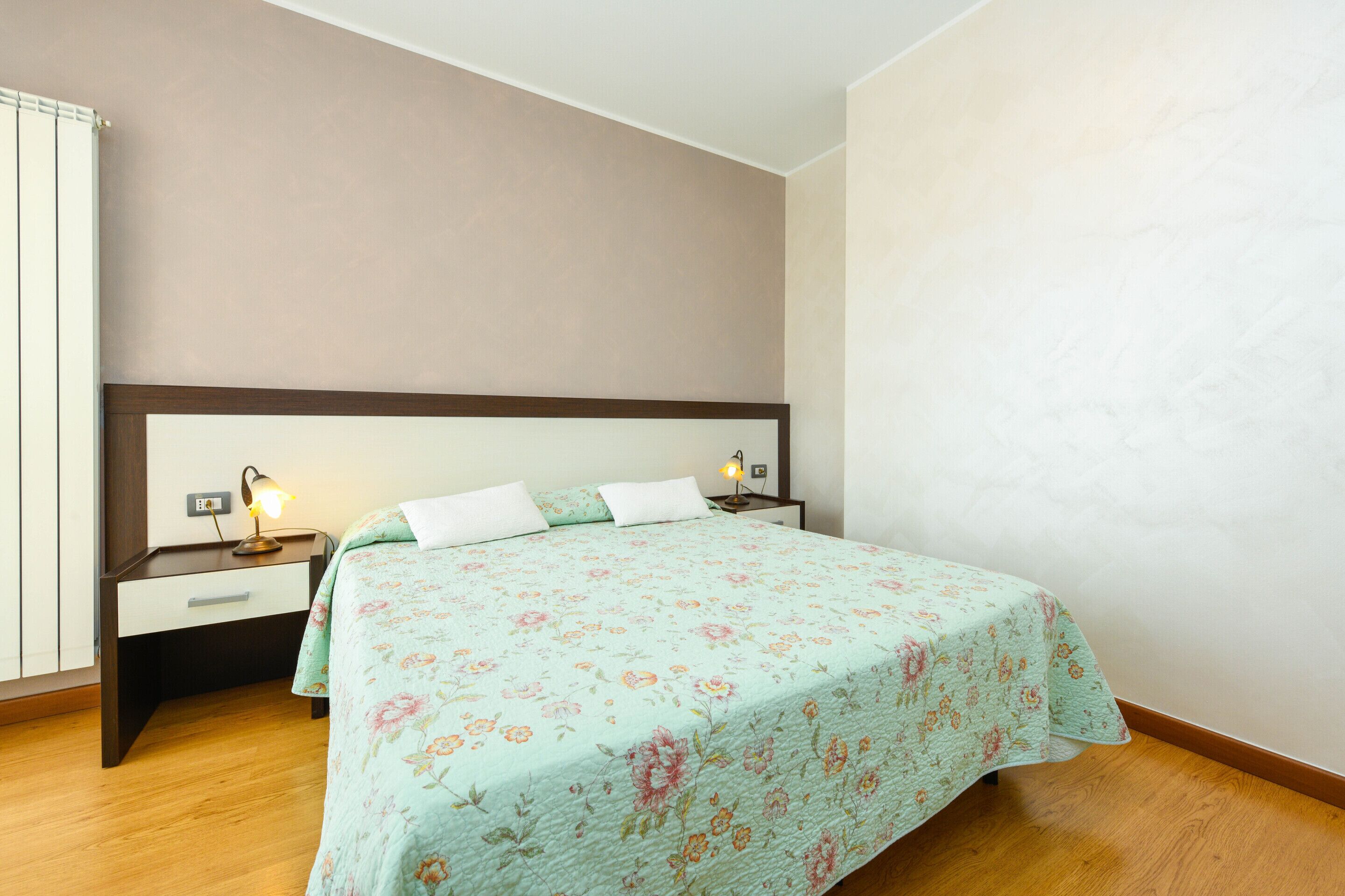 A bedroom with a bed, bedside tables, and a nightstand.