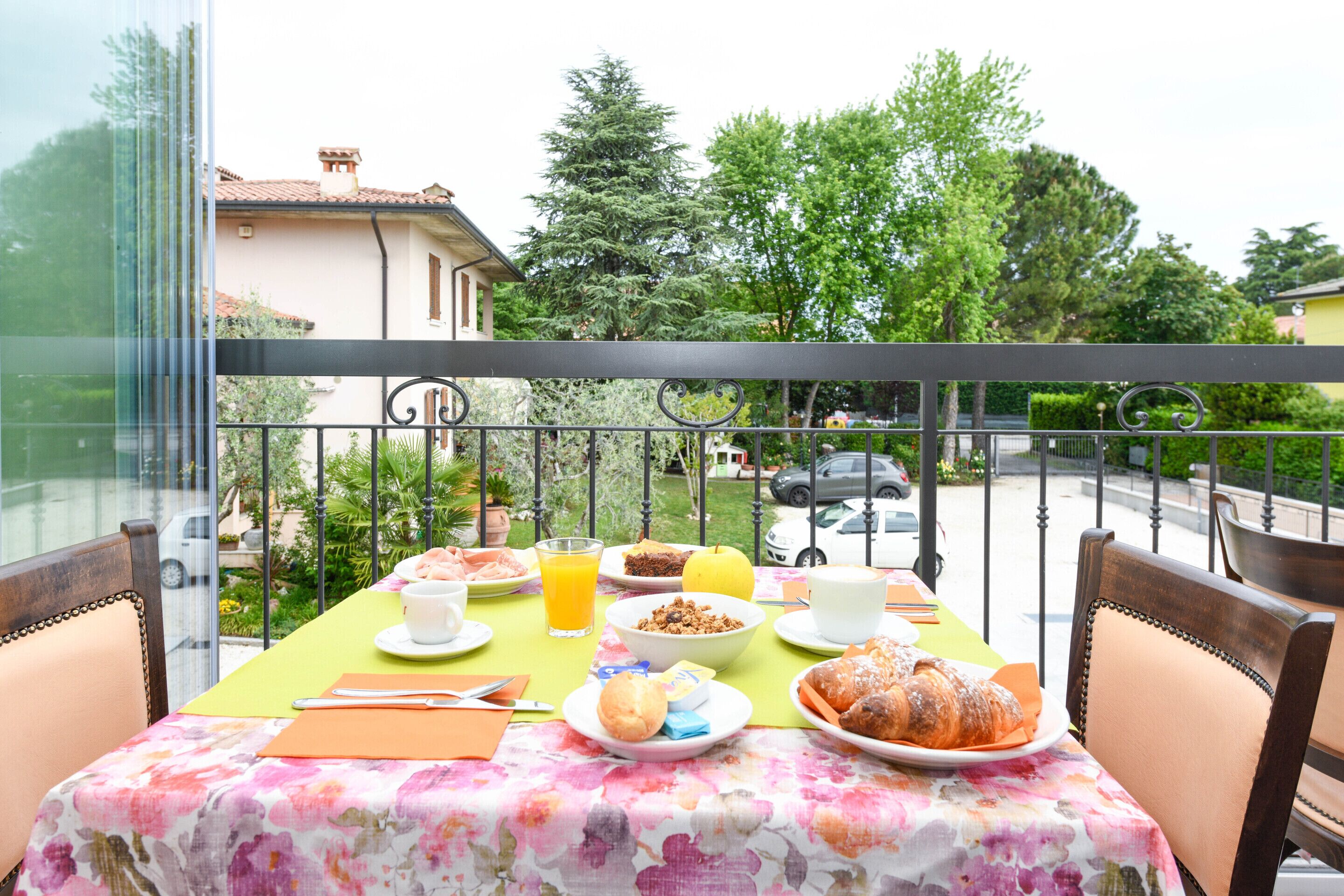Un balcon avec une table préparée pour le petit-déjeuner, donnant sur une rue résidentielle.