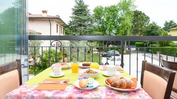 Un balcon avec une table préparée pour le petit-déjeuner, donnant sur une rue résidentielle.