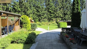 A patio area with outdoor seating, a pathway leading to a building, and a garden with various plants. - Pension Haus Mückenheim (Oberharz am Brocken)