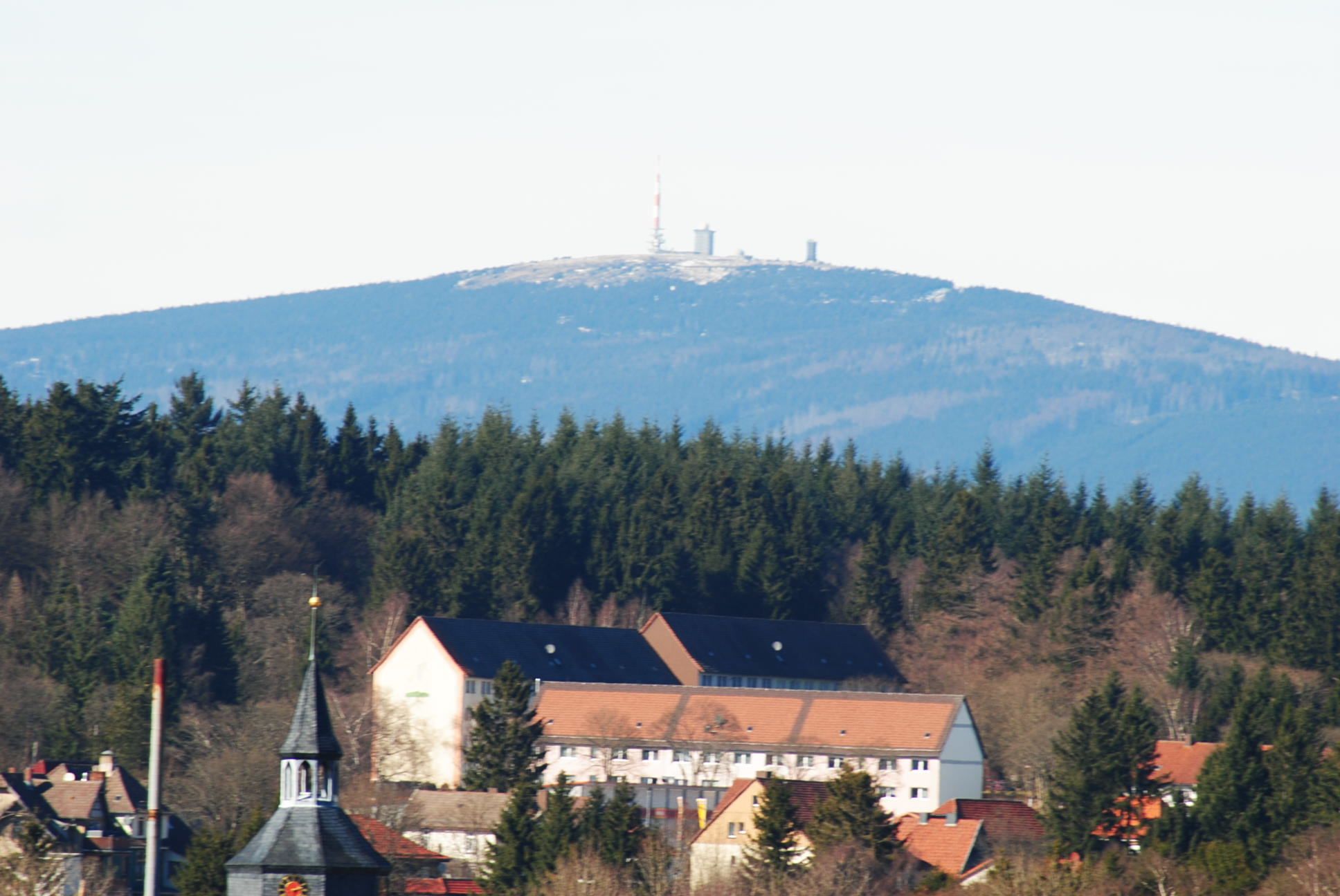A mountain with a church and residential buildings at its base.
