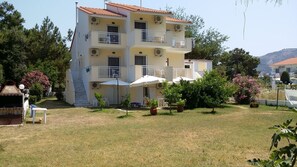 A multi-story building with balconies, outdoor seating, and a grassy courtyard. - Villa Iris (Thasos)