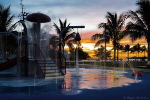 A water park with a slide, a water fountain, and palm trees at sunset. - ISLAND TIME at The Truman Annex in Key West (Key West)
