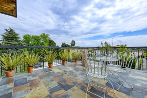 Una terraza con plantas en macetas y sillas de metal.