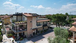 A multi-story building with balconies, outdoor seating, and potted plants. - B&B America (Sirmione)