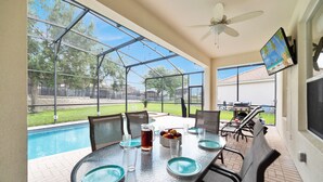 A covered outdoor dining area with a pool view, a ceiling fan, and a TV mounted on the wall. - Awesome! 6BR 4BA Luxury, Games, 2 Waterslides (Four Corners)