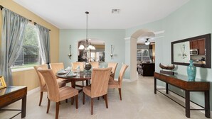 A dining area with a round table, chairs, and a chandelier. There is a kitchen in the background with a microwave and cabinets. - Awesome! 6BR 4BA Luxury, Games, 2 Waterslides (Four Corners)