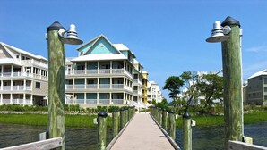 A wooden boardwalk leading to a waterfront property with multiple balconies and a green roof. - Bright, fun 5-bedroom townhouse in exclusive gated community with free WiFi, an indoor/outdoor pool, private bayside beaches, a restaurant, and more! (Ocean City)