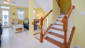 A staircase with wooden railings and white steps, leading to a second floor. - Bright, fun 5-bedroom townhouse in exclusive gated community with free WiFi, an indoor/outdoor pool, private bayside beaches, a restaurant, and more! (Ocean City)