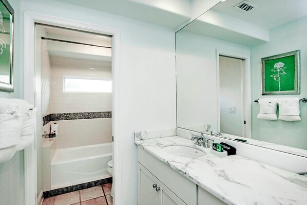 A modern bathroom with a walk-in shower, a large mirror, and a marble countertop.