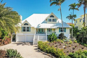 A two-story house with a white exterior, green shutters, and a covered front porch.