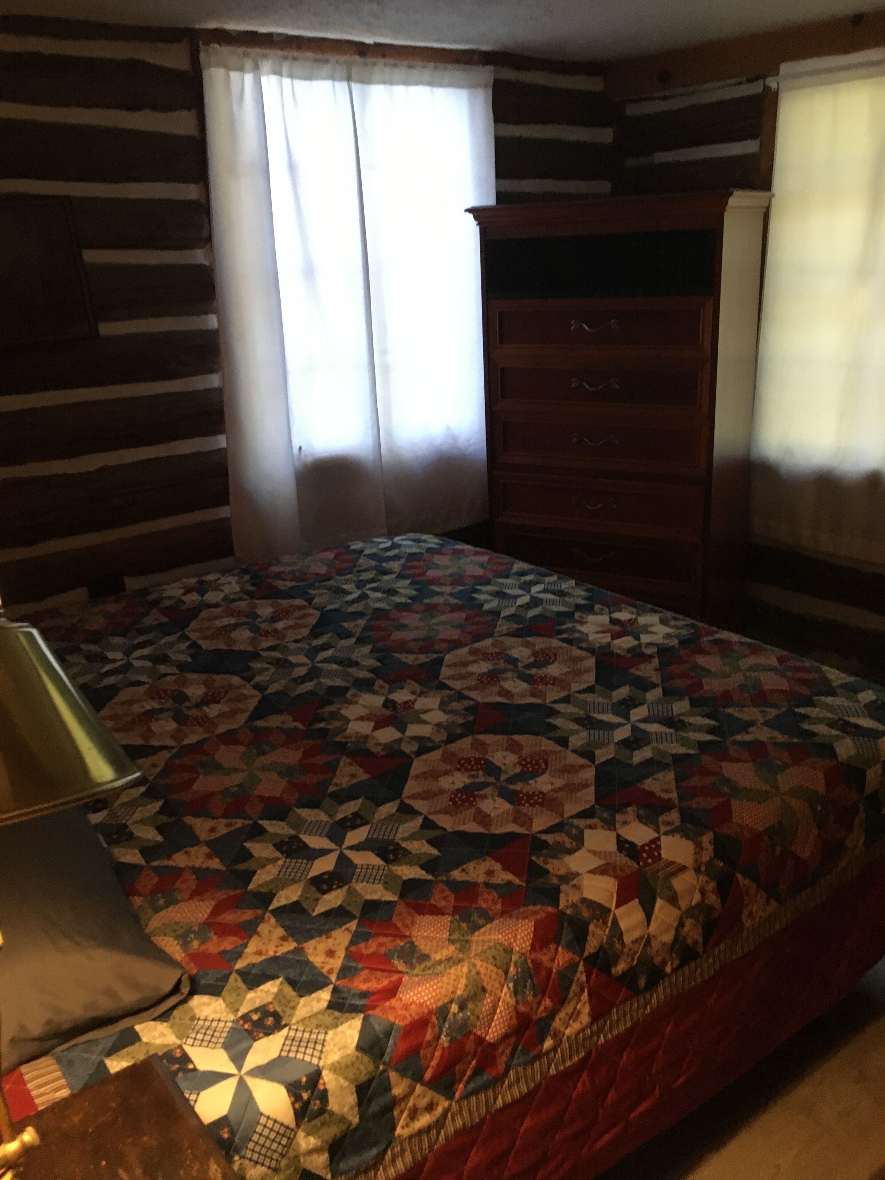 A room with a bed, a dresser, and a lamp.