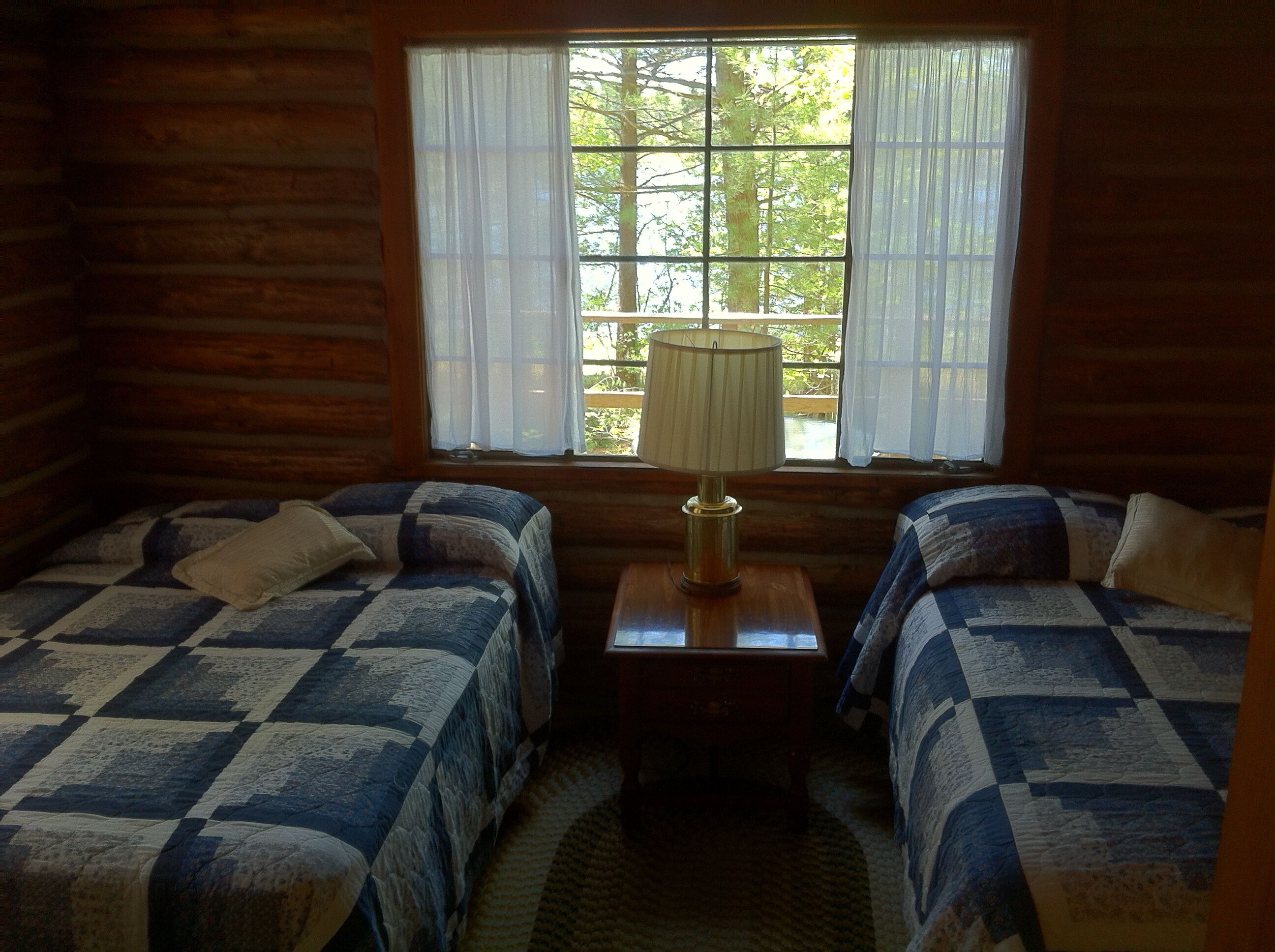 Une cabine comprenant deux lits, une petite table et une fenêtre avec des rideaux.