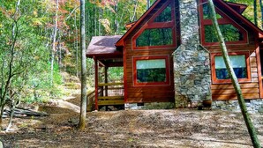 A cabin with a stone chimney, wooden exterior, and a deck. - Unique -Oliver Creek Cabin in Wilderness-PRIVATE-King Bed, WiFi, Hot Tub, Hiking (Ellijay)