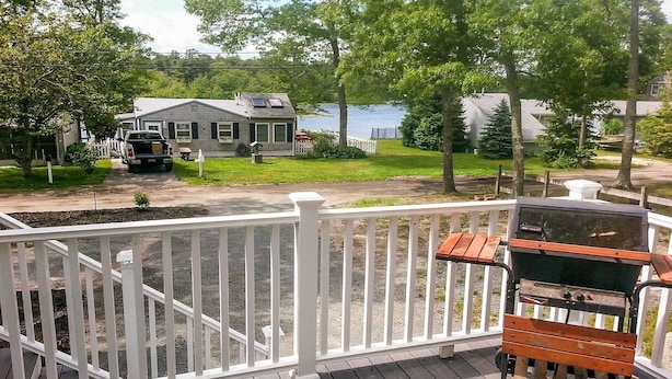 Une terrasse avec un barbecue et une clôture blanche.