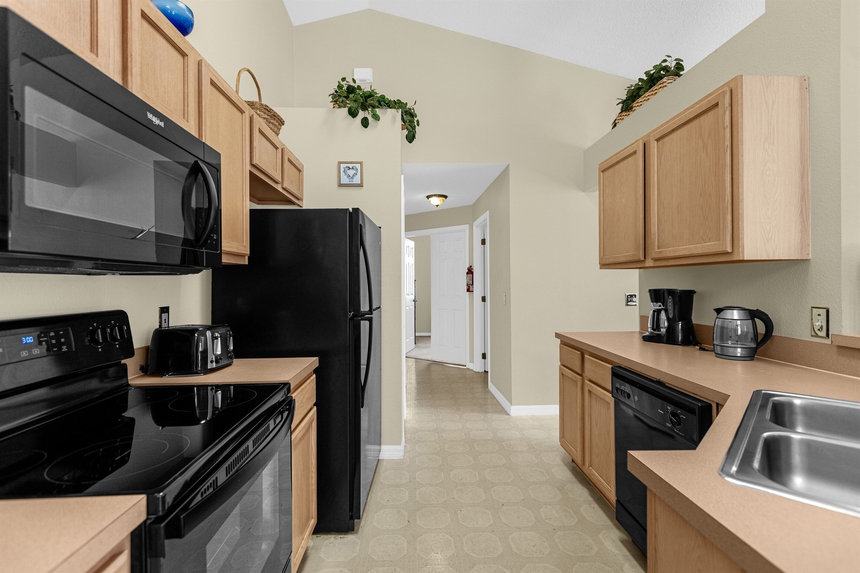 Una cocina moderna con electrodomésticos negros, armarios de madera y un lavamanos de acero inoxidable.