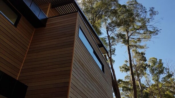 A modern building with horizontal wooden siding and a large window.