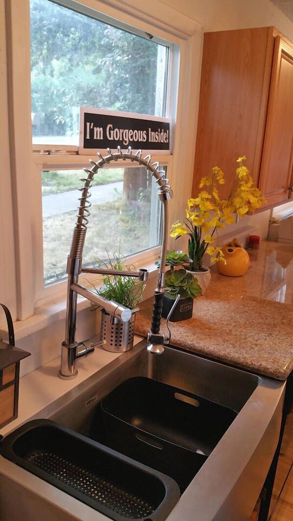 Enjoy a kitchen with a window view of lush greenery and a unique faucet, perfect for cooking up a meal.
