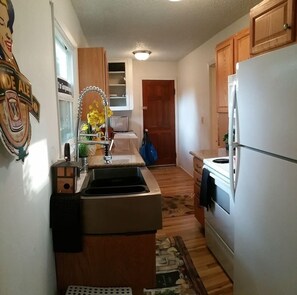 Kitchen features a central island with sink and stovetop, wooden cabinets, and a refrigerator.