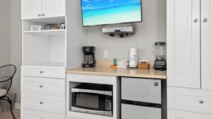 A compact kitchenette with a flat-screen TV, a coffee maker, a blender, and a microwave.