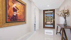 A hallway with a large framed painting, a modern door, and a vase with flowers on a table. - Best Cellar - The VIntage Holiday Houses (POKOLBIN)