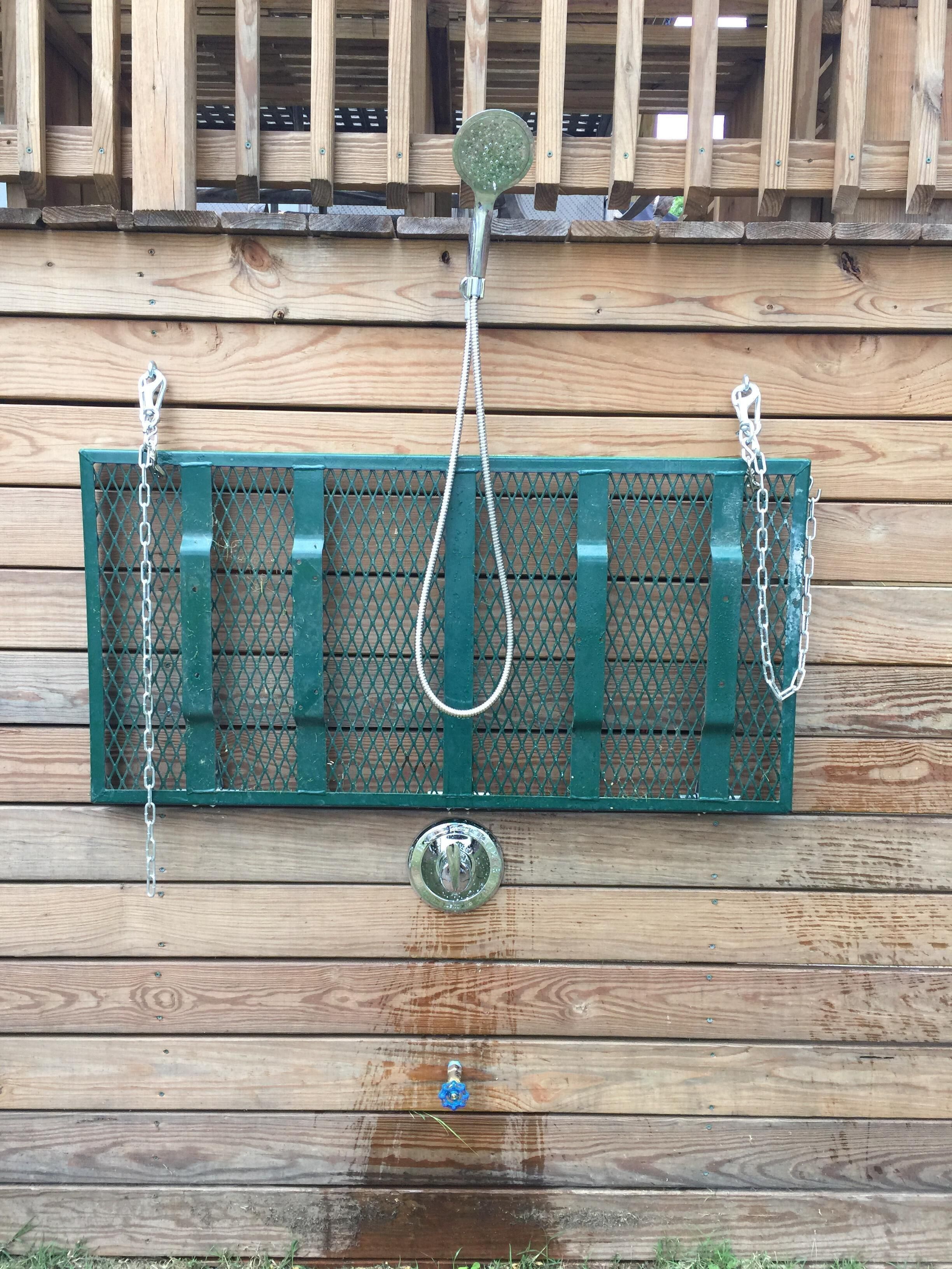 A green metal grill with a chain and a round object hanging from it, mounted on a wooden wall.