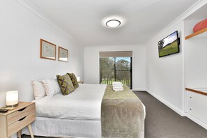 A hotel room with a bed, bedside tables, a TV, and a window with a view.