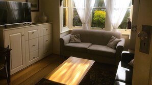 Una sala de estar acogedora con un sofá, una mesita de centro y un televisor sobre un mueble.