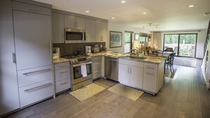 A modern kitchen with stainless steel appliances, a large island, and a dining area with a view. - Great 2 bed townhouse. This is the best location in Ketchum! (Ketchum)