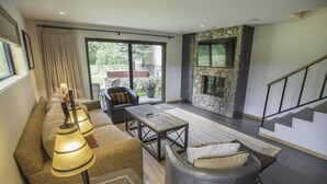 A modern living room with a stone fireplace, a sofa, a coffee table, and a large window. - Great 2 bed townhouse. This is the best location in Ketchum! (Ketchum)