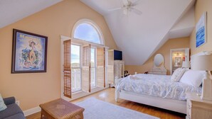 A bedroom with a bed, a dresser, a nightstand, a window with shutters, a ceiling fan, and a framed picture on the wall. - Nantucket Charm | 280 ft from the Beach | Private Pool (Virginia Beach)