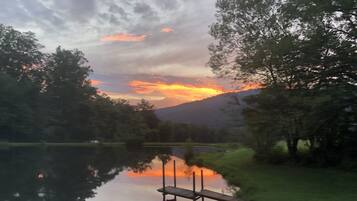 Un lac paisible avec une jetée en bois qui s’avance sur l’eau, entouré d’arbres et avec une montagne en arrière-plan.