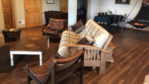 A spacious living room with a wooden floor, a sofa, a chair, a coffee table, and a hammock. - Beautiful valley views & next to Big Spring State Park (Doylesburg)