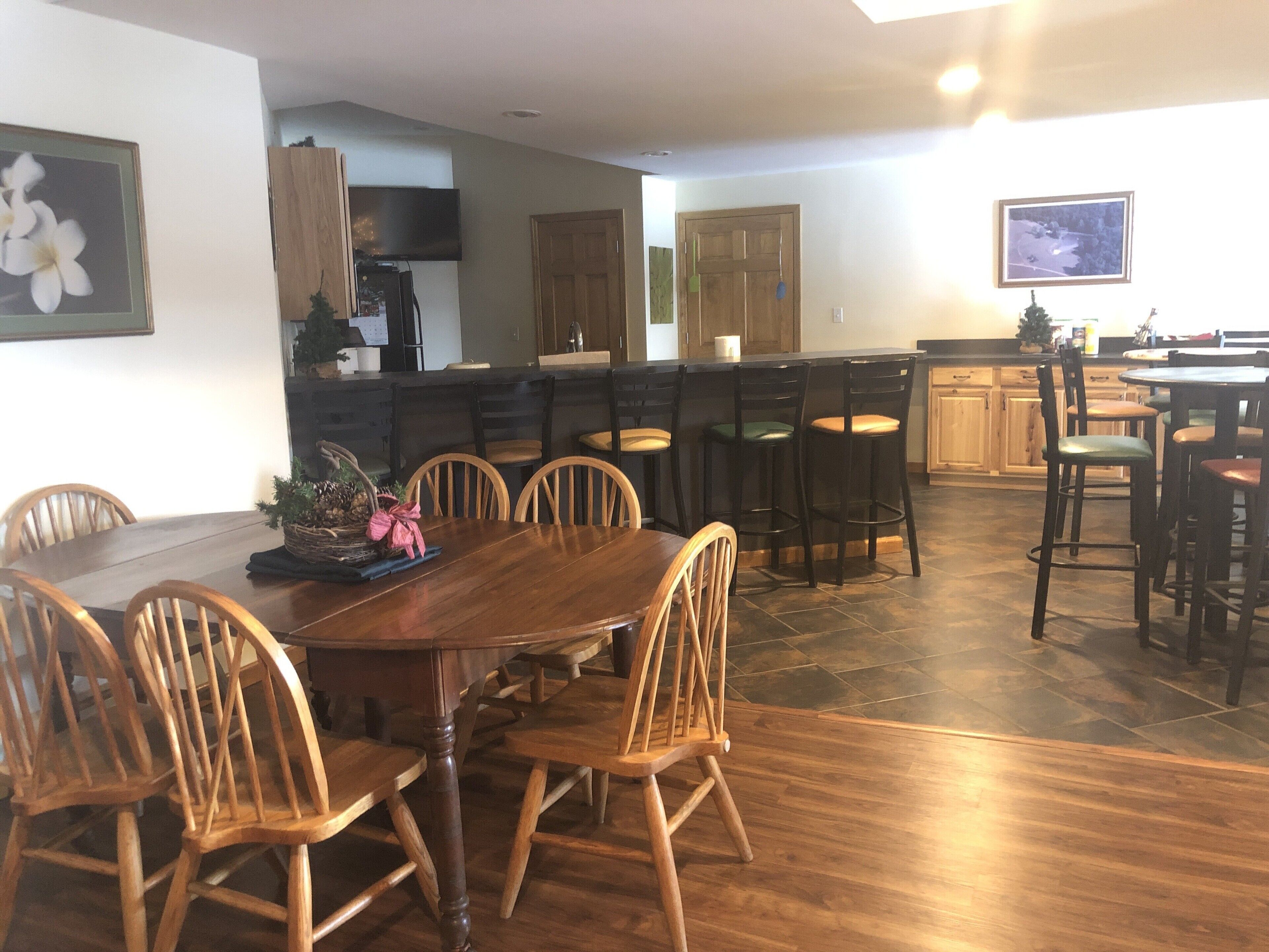 A spacious kitchen with a central island, wooden chairs, and a dining table.