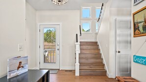 A staircase with wooden steps and white railings leading to a second floor. - Castlebar | Luxury Salt Marsh Landing Waterfront w/ Private Pier, Bayfront Dock, Sunsets & Fireplace (Chincoteague Island)