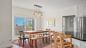 A modern kitchen with a wooden dining table, chairs, and a built-in refrigerator. - Castlebar | Luxury Salt Marsh Landing Waterfront w/ Private Pier, Bayfront Dock, Sunsets & Fireplace (Chincoteague Island)