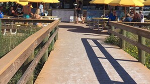 Un restaurante llamado Paradise Grill con mesas al aire libre y sombrillas amarillas.