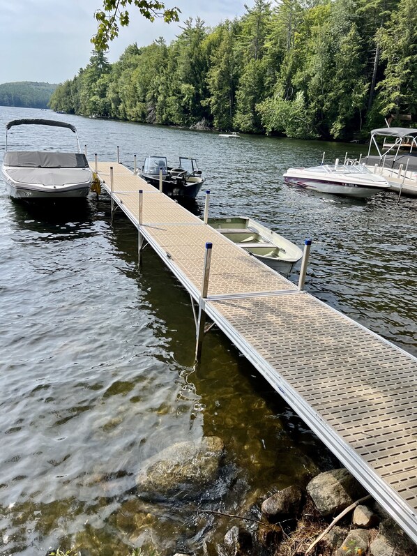 A dock with boats moored on a calm lake, surrounded by dense forest. - A beautiful lake view cabin on Friends Lake (Chestertown)