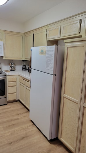 A kitchen with wooden cabinets, a refrigerator, a coffee maker, and a stove. - Snowcreek Resort Vacation Rental 617 (Mammoth Lakes)