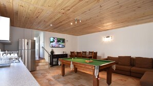 A modern kitchen with a built-in dishwasher, a stainless steel refrigerator, and a dining area with a pool table. - Enjoy the waterfront and outdoor activities while staying at our place! (Lota)