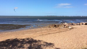 A beach with a rocky shoreline, clear blue sky, and a distant view of the ocean. - Enjoy the waterfront and outdoor activities while staying at our place! (Lota)