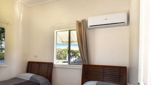 A room with two beds, a window with curtains, an air conditioning unit, and a ceiling fan. - Enjoy the waterfront and outdoor activities while staying at our place! (Lota)