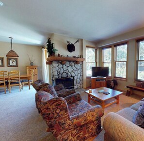 A living room with a stone fireplace, a television, and a sofa set. - Snowcreek Resort Vacation Rental 903 (Mammoth Lakes)
