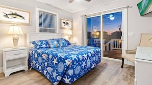 Ein Schlafzimmer mit einem Bett, zwei Nachttischen, einem Deckenventilator und einem großen Fenster mit Blick auf die Stadt.