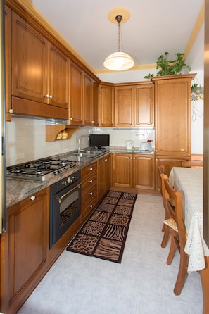 A kitchen with wooden cabinets, a gas stove, a microwave, and a dining area with a table and chairs.