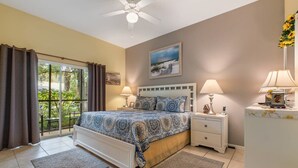 A bedroom with a bed, two bedside tables, a ceiling fan, a large window with curtains, and a view of greenery outside. - Bahama Bay- 3 bedroom condo with amenities (Davenport)