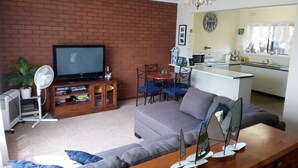 A living room with a television, a fan, a sofa, and a wooden coffee table. - Rigby's cozy hideout (St Leonards)