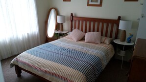 A neatly made bed with striped bedding, a wooden headboard, and two bedside lamps. - Rigby's cozy hideout (St Leonards)