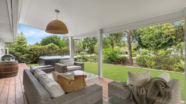 Un espacio de estar al aire libre cubierto con mobiliario de mimbre, un jacuzzi y una pérgola.