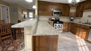 A kitchen with wooden cabinets, a granite countertop, stainless steel appliances, and pendant lighting. - Come to Pensacola White Sand beaches, in a great location 🏚️ (Pensacola)
